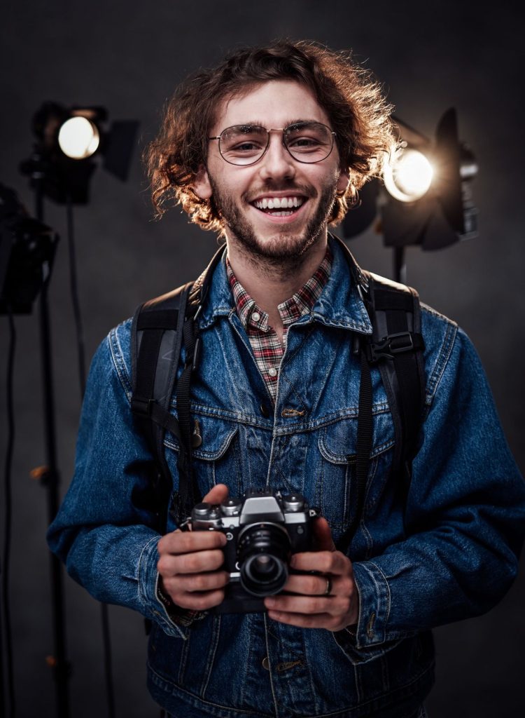 young photographer holds a camera studio portrait Y6PFWET